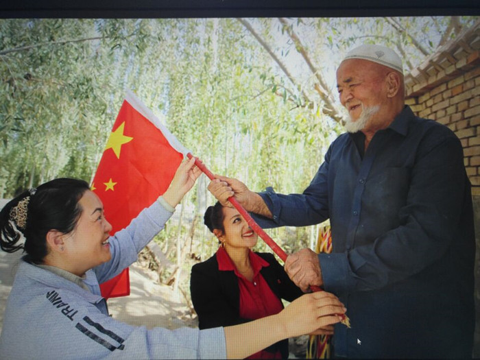 1506949290259077929.jpg 9月29日,自治区人民政府办公厅干部刘长缨和她在喀什地区疏勒县阿拉力乡马木克村3组的结亲户尤努斯·斯马义一家在新盖的富民安居房前挂国旗,共同给祖母亲过生日。1_副本.jpg